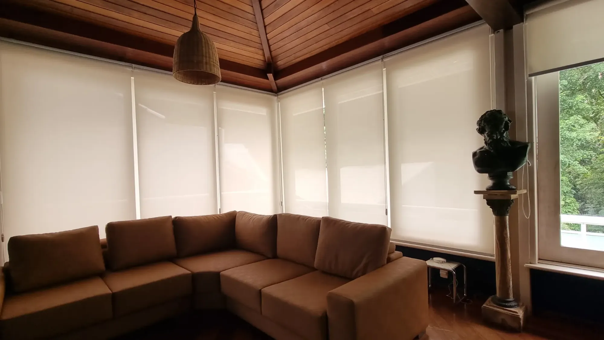 Sala com persianas rolô em janelas de canto e sofá em L